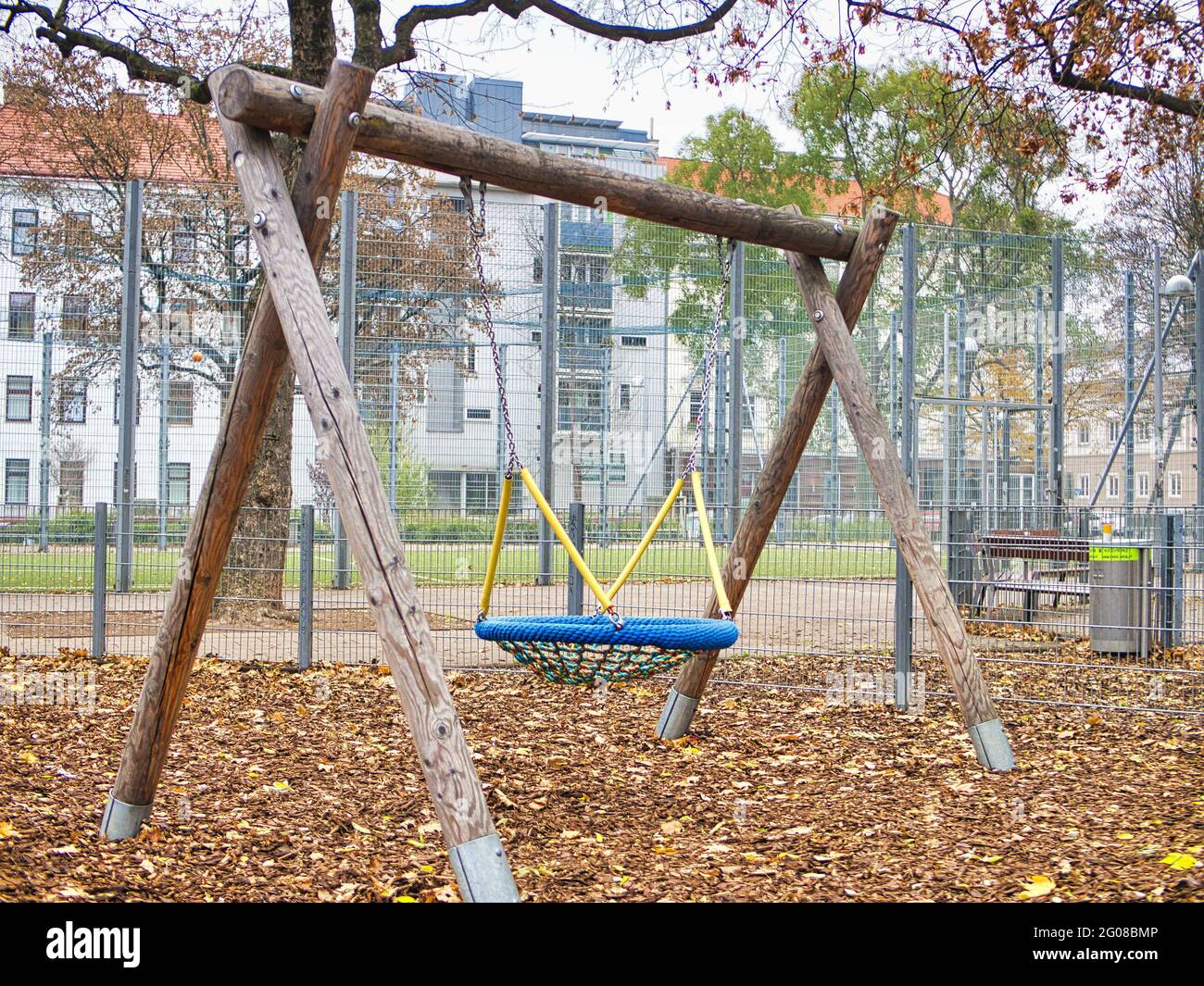 Columpios de madera hechos a mano en un parque cubierto de hojas