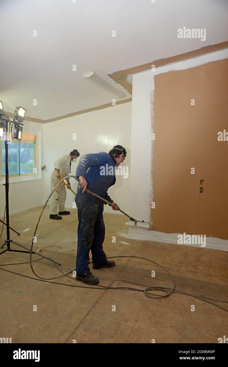 un comerciante que utiliza un equipo de pulverización sin aire para pintar  una capa de imprimación en las paredes de un edificio comercial Fotografía  de stock - Alamy