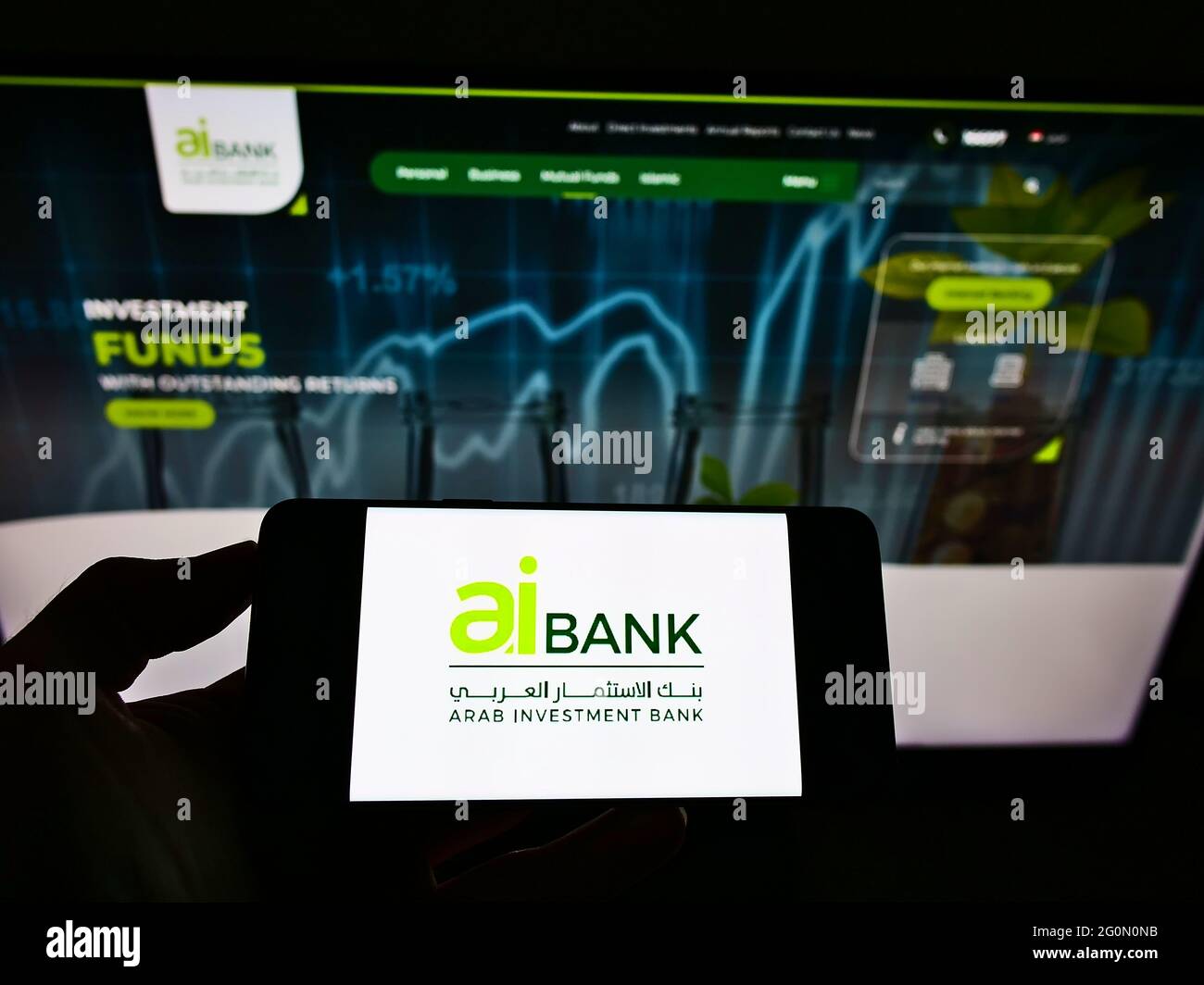Persona con smartphone con el logotipo de la empresa financiera Arab Investment Bank (AIB Egipto) en la pantalla frente al sitio web. Enfoque en la pantalla del teléfono. Foto de stock