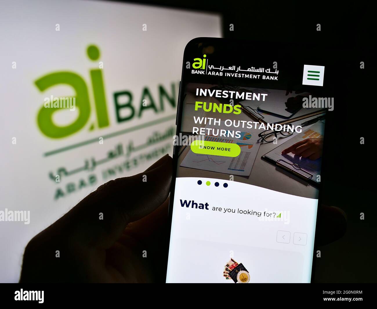 Persona que sostiene el teléfono móvil con el sitio web de la empresa financiera Arab Investment Bank (AIB Egipto) en la pantalla delante del logotipo. Enfoque en la pantalla del teléfono. Foto de stock