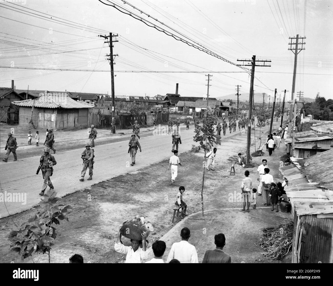 Los residentes de Inchon regresan a las calles y a la forma normal de vivir como marines de los EE.UU. Marchan a través de para comprometer al enemigo en Seúl, 17 de septiembre de 1950 Foto de stock