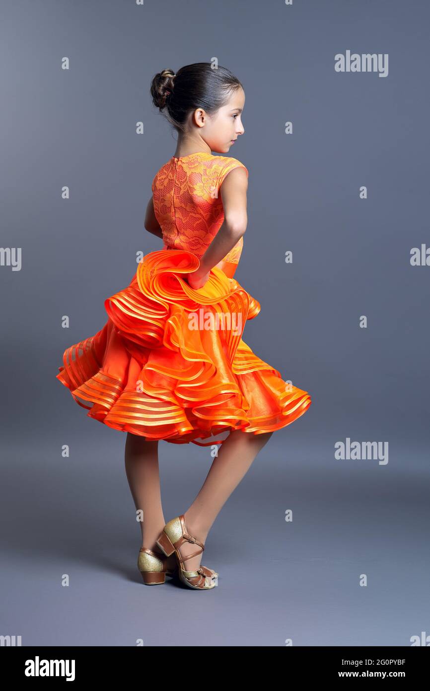 Niña en un vestido deportivo naranja en movimiento de danza sobre fondo gris Fotografía de stock - Alamy
