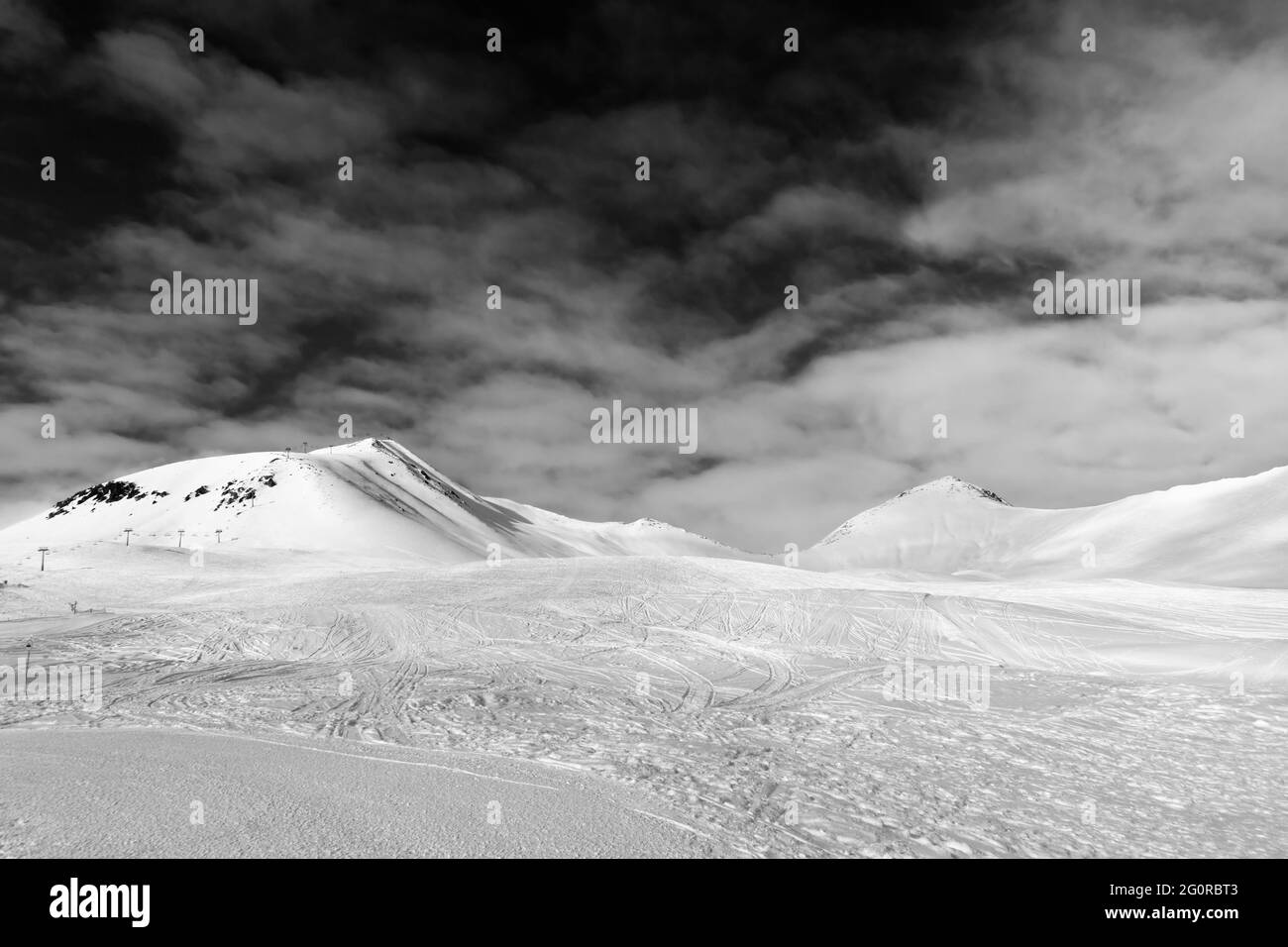 Pista de esquí con estampado de esquís, snowboards y pies, montañas nevadas y cielo con nubes. Montañas del Cáucaso, Georgia, región Gudauri. Gran angular Foto de stock