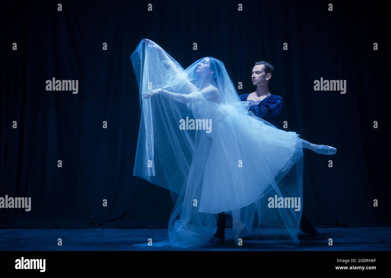 Mujer joven con vestido de boda y hombre, dos bailarinas de ballet en el  baile artístico aislado sobre fondo oscuro Fotografía de stock - Alamy
