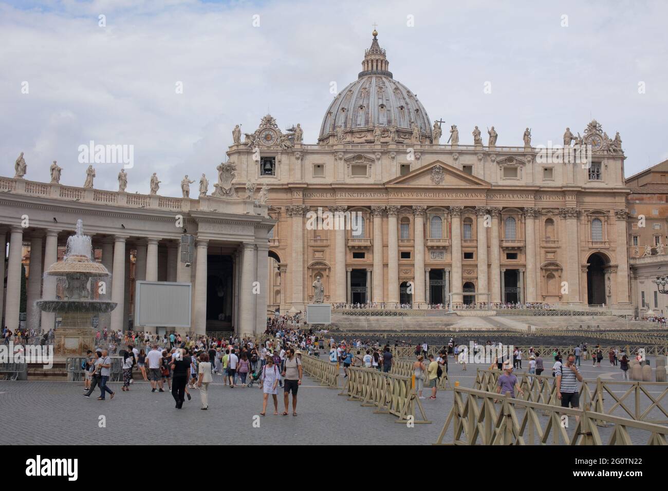 Gente en la plaza de San Pedro en el Vaticano contra la basílica de San Pedro, la obra más famosa de la arquitectura renacentista y la iglesia más grande del mundo Foto de stock