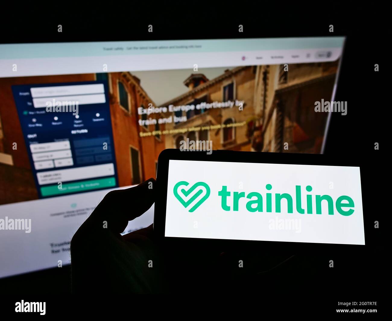 Persona con smartphone con el logotipo de British Ticket Platform TRAINLINE  plc en la pantalla frente al sitio web. Enfoque en la pantalla del teléfono  Fotografía de stock - Alamy
