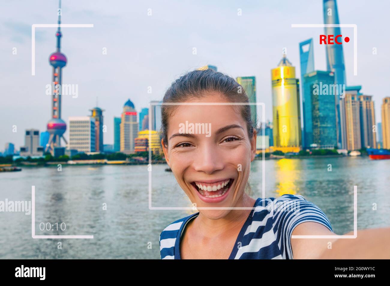 Feliz viaje de China selfie mujer de turismo asiático vlogging en línea grabación vídeo vlog videoblog. Chica joven sonriente sosteniendo el teléfono con cámara en el Bund Foto de stock