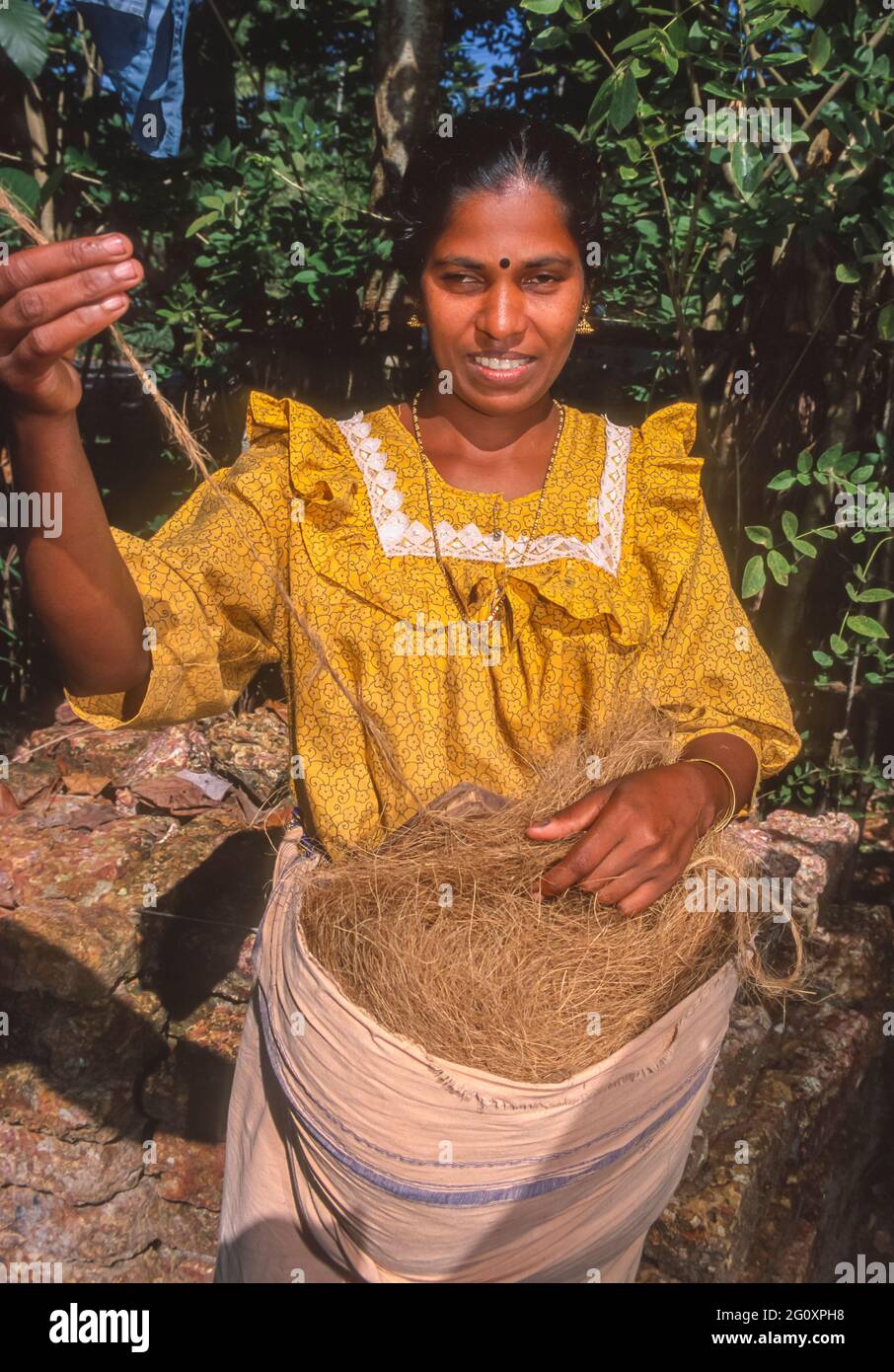 ALLEPPEY, KERALA, INDIA - Mujer hilando coir, fibra de coco, en el cordel en un pequeño taller. Foto de stock
