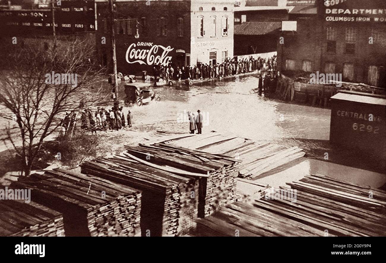 Automóvil vintage pasando por calles inundadas en Columbus, Georgia, mientras los espectadores miran desde tierra seca. El río Chattahoochee, que corre junto al Uptown Columbus, desbordó sus orillas a mediados de febrero de 1900. Foto de stock