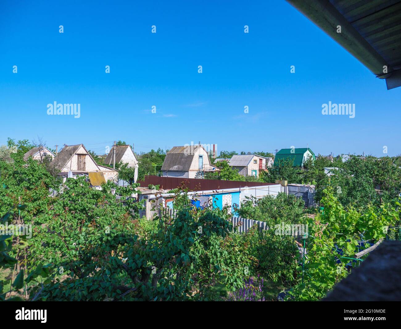 Vista desde el balcón superior sobre las casas de campo de dos pisos dacha con pequeños parches de terreno con jardines verdes. El concepto de patrimonio de la época soviética. Foto de stock