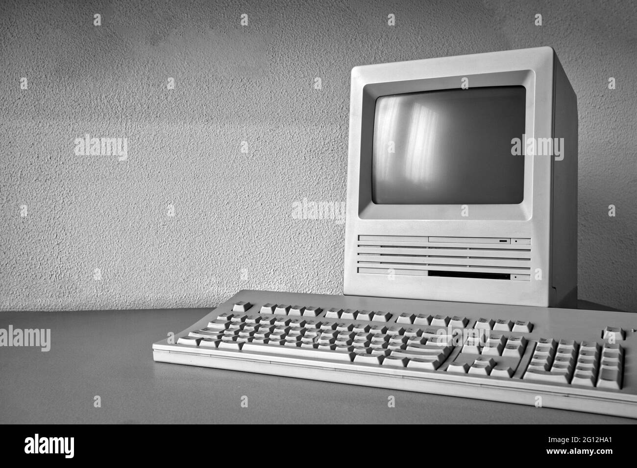 Monitor antiguo vintage y ordenador en el escritorio, retro lugar de trabajo con copia de negocios espacio, tecnología, concepto de Internet cerca de la pared blanca. Foto de stock
