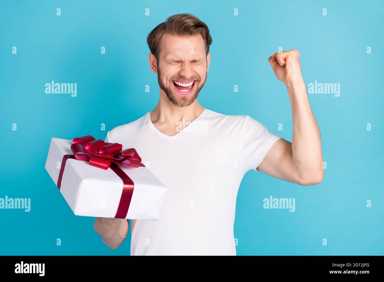 Retrato de persona alegre asombrada puño arriba ojos cerrados sostener  giftbox aislado sobre fondo de color azul Fotografía de stock - Alamy