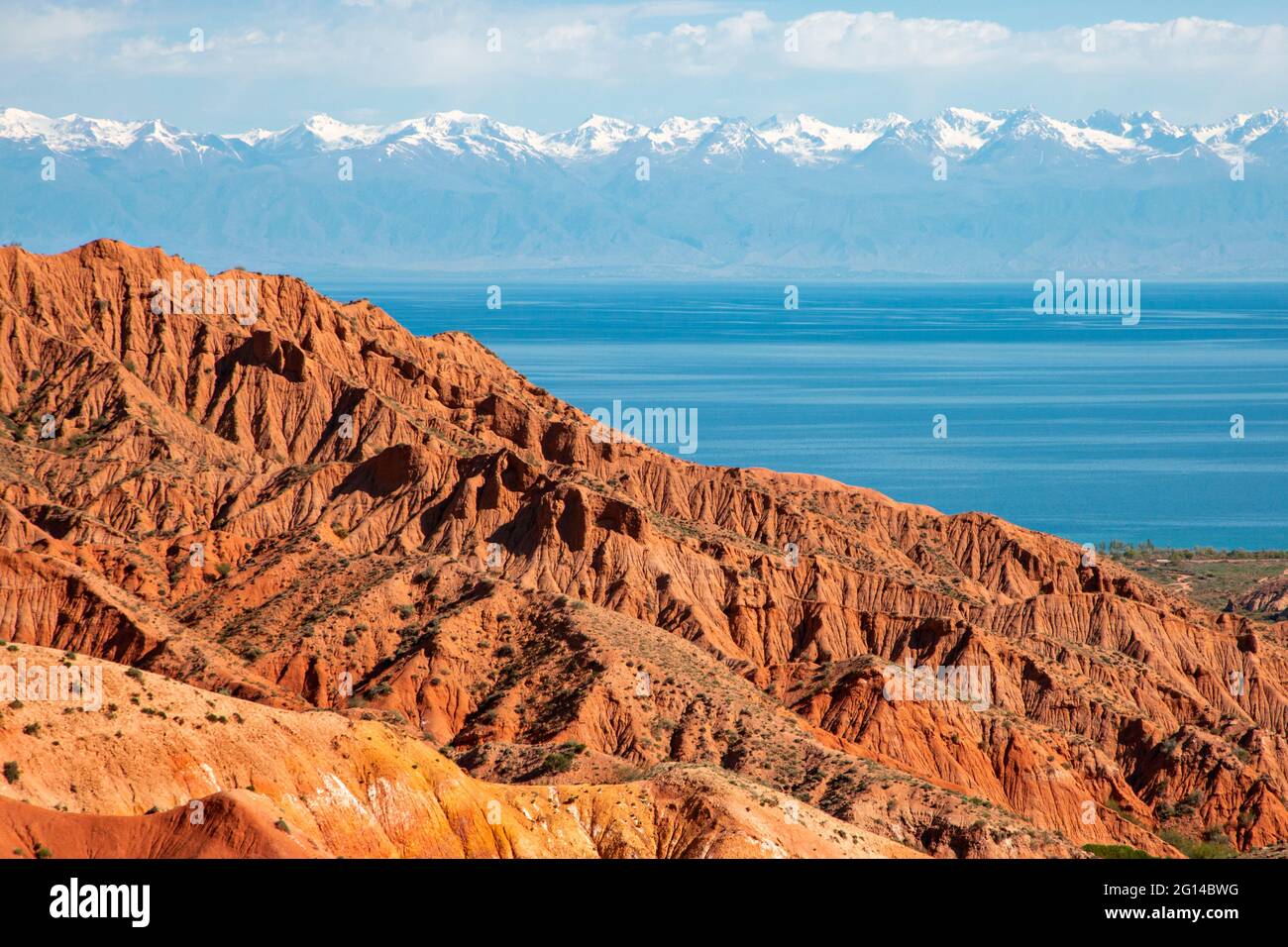 Formaciones rocosas rojas con el lago Issyk Kul en el fondo en Kaji Say, Kirguistán. Foto de stock
