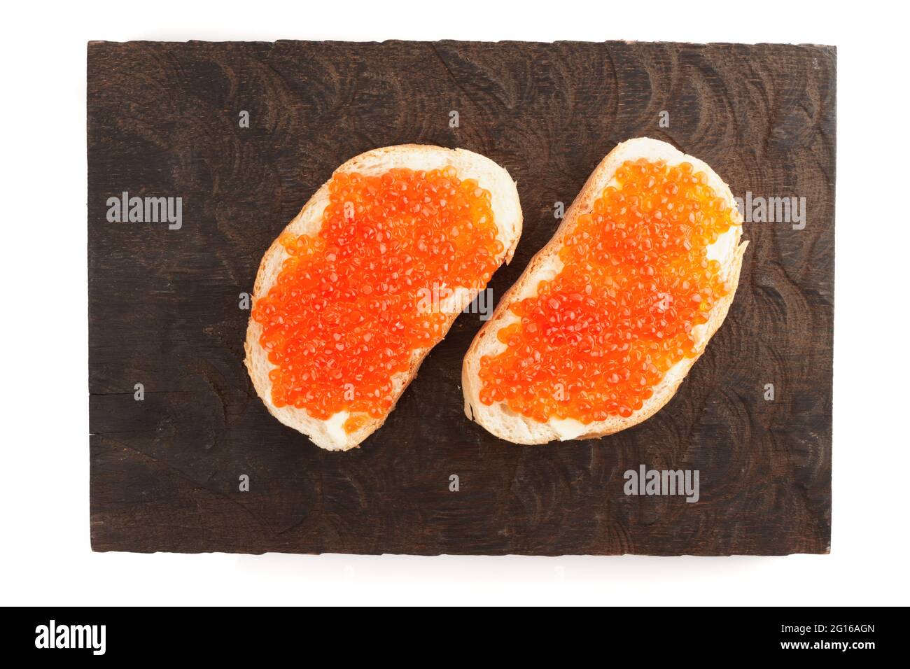 Sándwiches abiertos con huevas de salmón sobre tabla de madera, aislados sobre fondo blanco Foto de stock