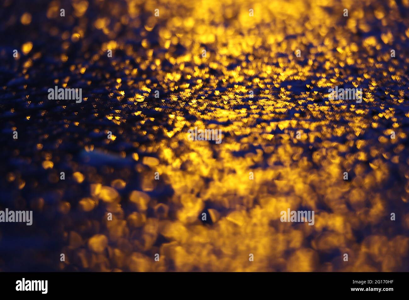 imagen abstracta de la luz amarilla que se refleja en una superficie negra irregular Foto de stock