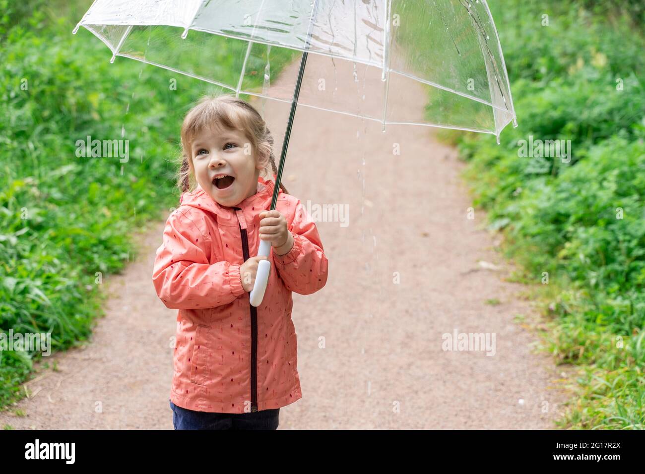 linda niña con un paraguas transparente se regocija en la lluvia de verano  Fotografía de stock - Alamy