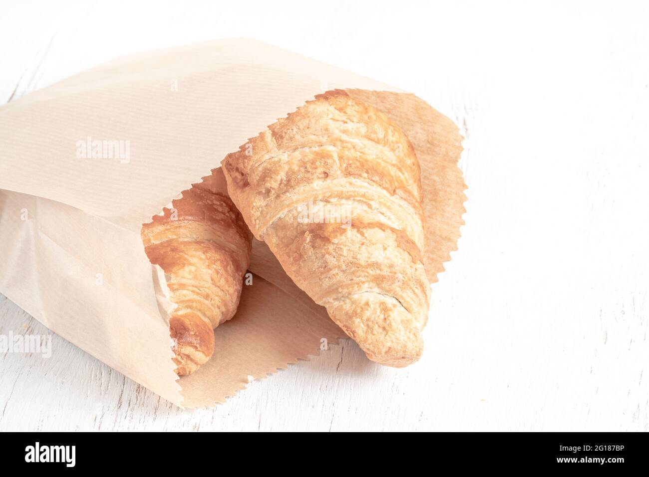 cierre un croissant crujiente en una bolsa de papel sobre la mesa  Fotografía de stock - Alamy