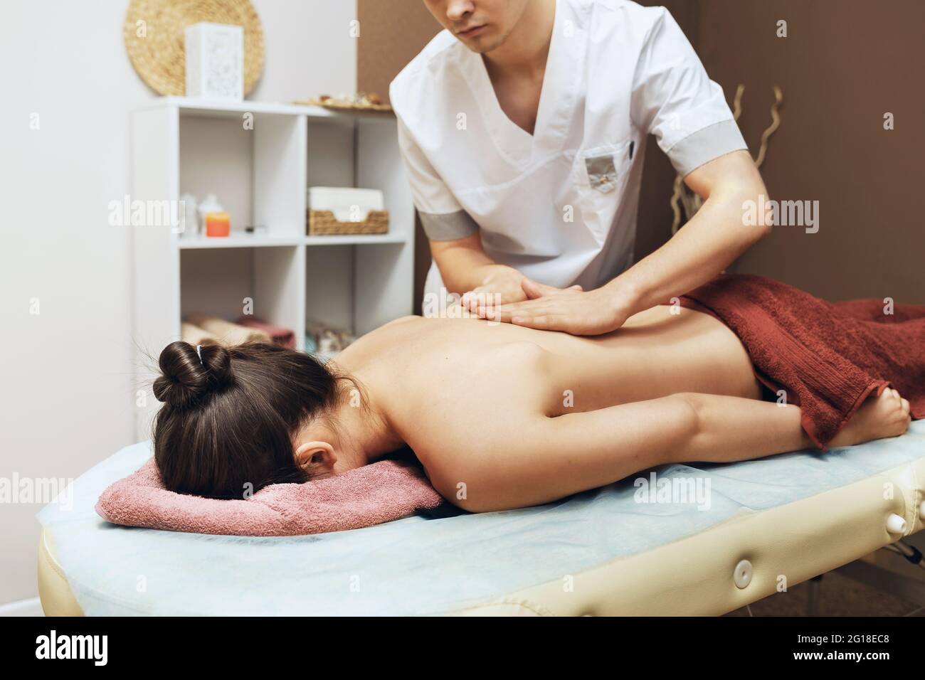 Un terapeuta de masaje profesional conduce un masaje de espalda para una mujer cliente en su oficina, terapia manual de la columna vertebral. Foto de stock