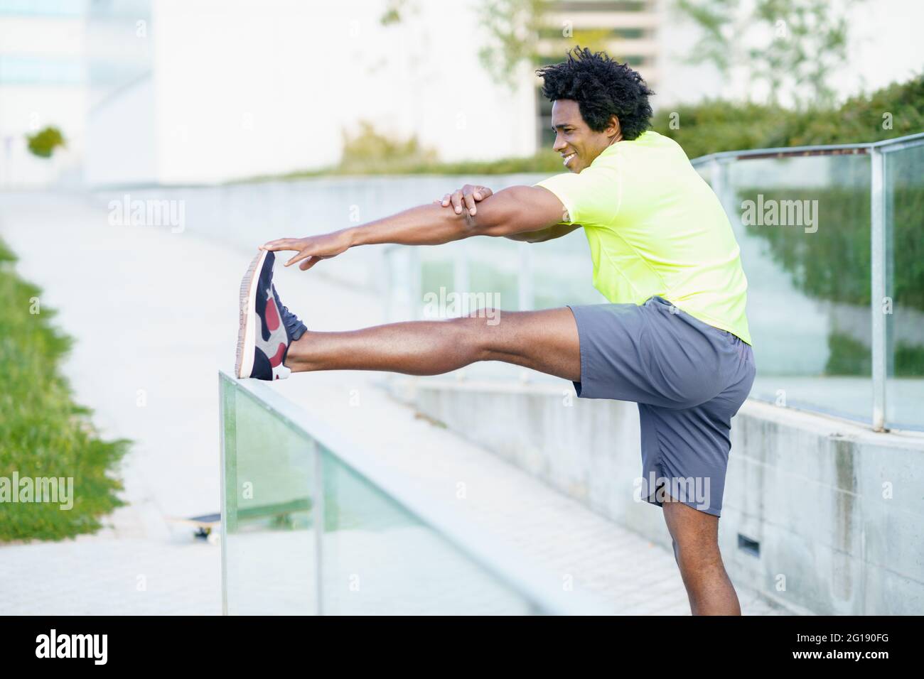 Hombre negro con pelo afro que se estira después de correr al aire libre. Foto de stock