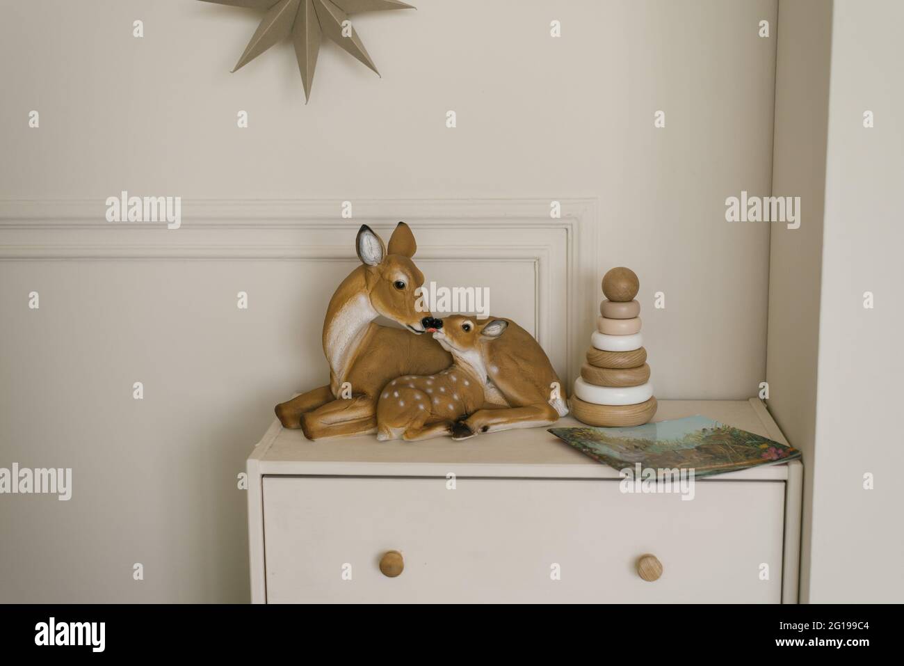 Figuras de ciervo y una pirámide de juguetes de madera para niños en el pecho de los cajones en el interior de la habitación moderna de los niños Foto de stock
