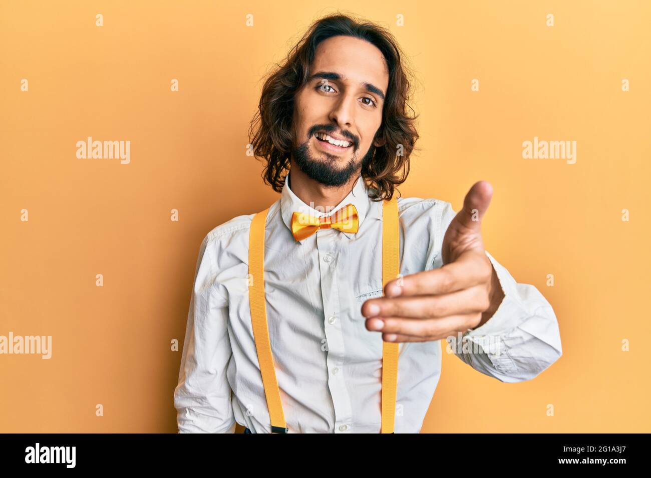 Joven hispano vestido hipster elegante mirada sonriente amable ofreciendo apretón de manos como saludo y bienvenida Fotografía de stock - Alamy Joven hispano vestido hipster elegante mirada sonriente amable ofreciendo apretón de manos como saludo y bienvenida Fotografía de stock - Alamy