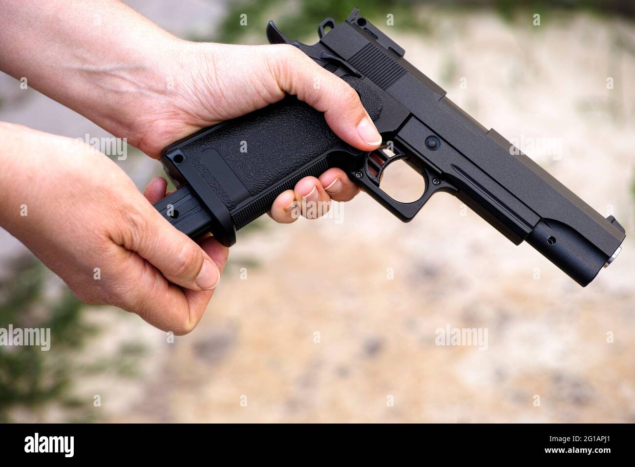 Una persona que vuelve a cargar una pistola de aire comprimido Foto de stock