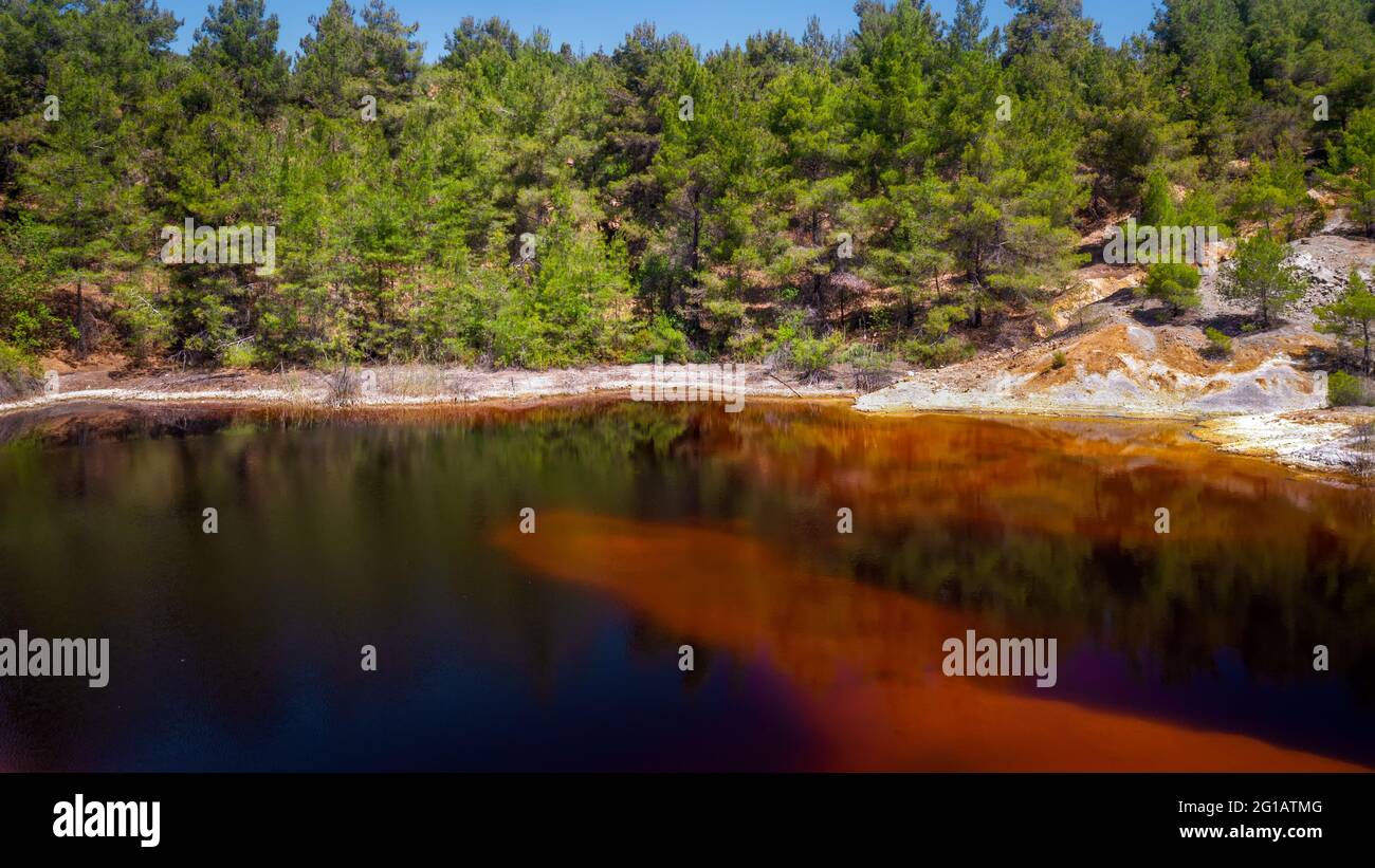 Orilla de un lago rojo tóxico en una mina a cielo abierto abandonada. Su color deriva de altos niveles de ácido y metales pesados Foto de stock