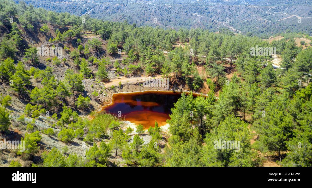 Restauración de bosques en el pozo de minería de opencast abandonado cerca de Kinousa, Chipre. Vista aérea del cráter de la mina de cobre y del lago rojo Foto de stock