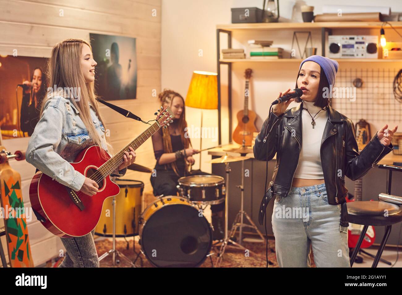 Banda femenina compuesta por tres chicas grabando canciones en el estudio Foto de stock