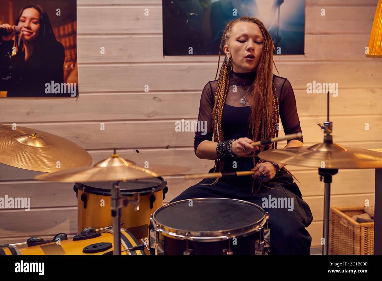 Chica sentada junto al tambor mientras grababa música en un estudio moderno Foto de stock