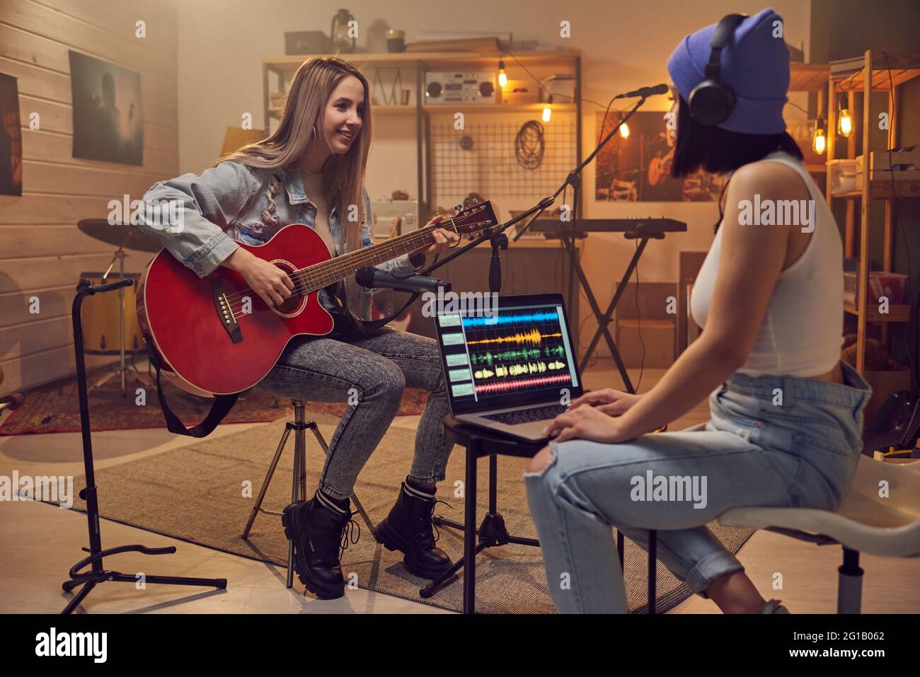 Dos mujeres jóvenes grabando nueva música delante del portátil Foto de stock