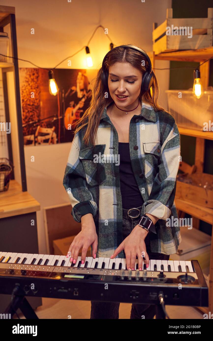 Mujer rubia tocando sintetizador y cantando en estudio Foto de stock