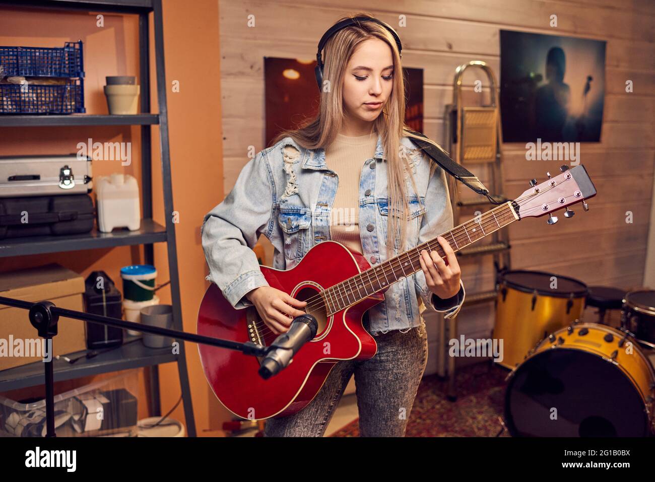 Chica con pelo rubio largo tocando la guitarra eléctrica en el estudio Foto de stock