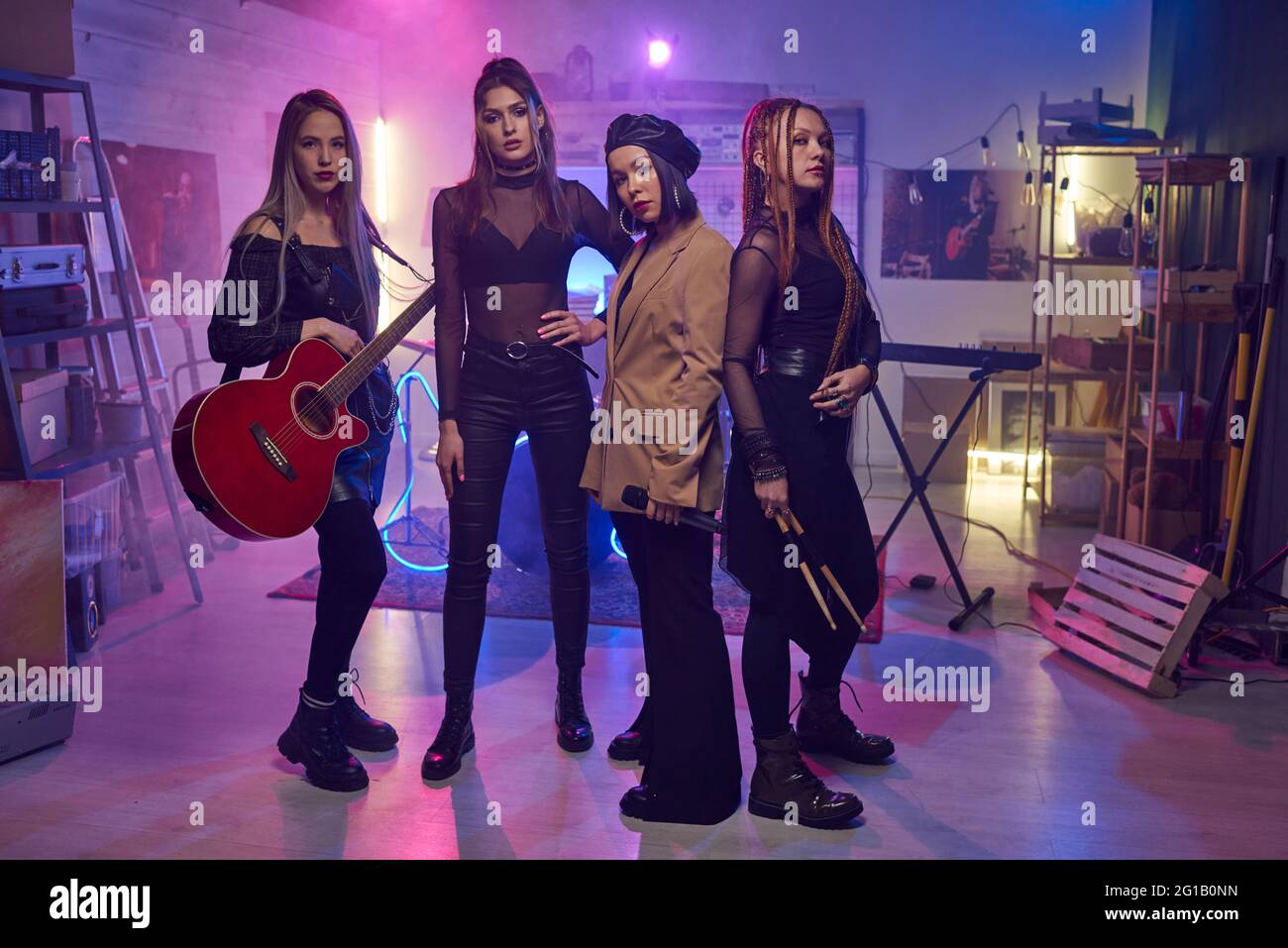 Grupo de mujeres jóvenes con instrumentos musicales de pie en estudio Foto de stock