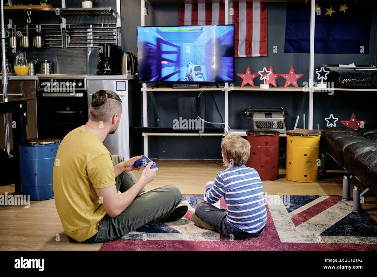 Vista posterior de un joven y un niño jugando a videojuegos en el suelo Foto de stock