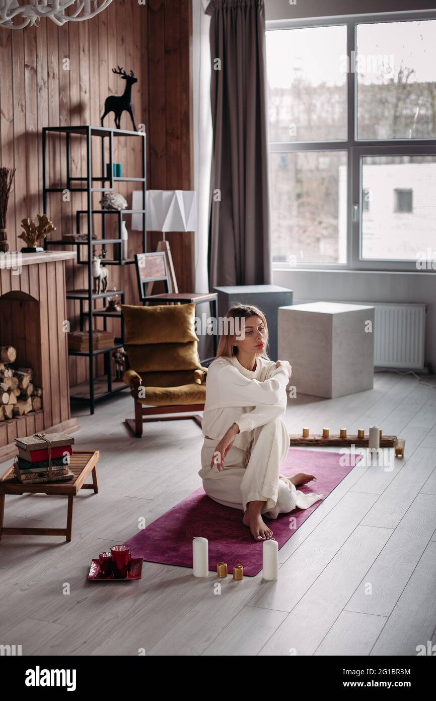 Hermosa niña joven con ropa deportiva ecológica de algodón blanco natural,  sentada en la alfombra en el acogedor interior del hogar Fotografía de  stock - Alamy