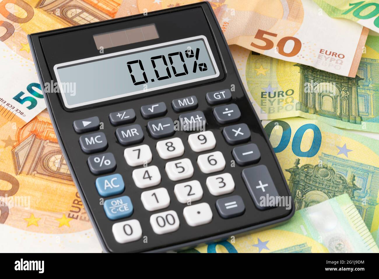 Calculadora que muestra el tipo de interés cero por ciento en los billetes en euros, concepto de préstamo barato Foto de stock