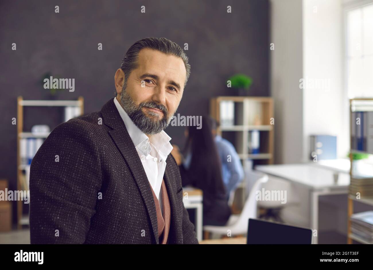 Retrato de un guapo ejecutivo senior de negocios contra un fondo de oficina borroso Foto de stock