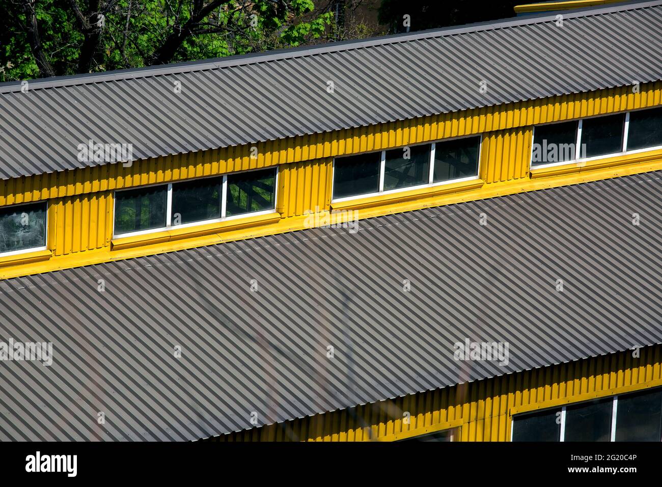techo doble de dos vertientes exterior con ventanas cubiertas con planchas  de hierro edificio de almacén industrial amarillo con revestimiento de  protección gris, vista superior al aire libre Fotografía de stock -