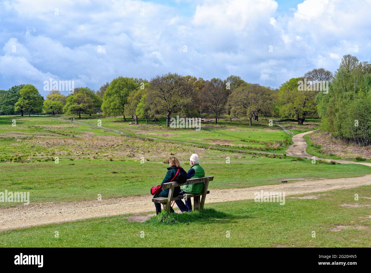 Pareja de ancianos sentada en el banco admirando la vista en un día de primavera en Richmond Park London Inglaterra Reino Unido Foto de stock