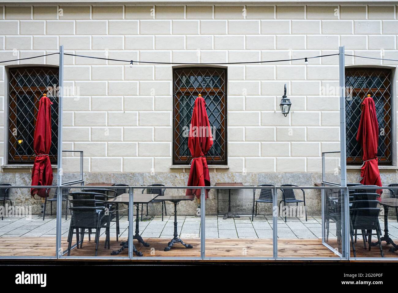 Sillas plegadas y sombrillas plegadas en la zona exterior de un restaurante durante la pandemia de Corona. Foto de stock