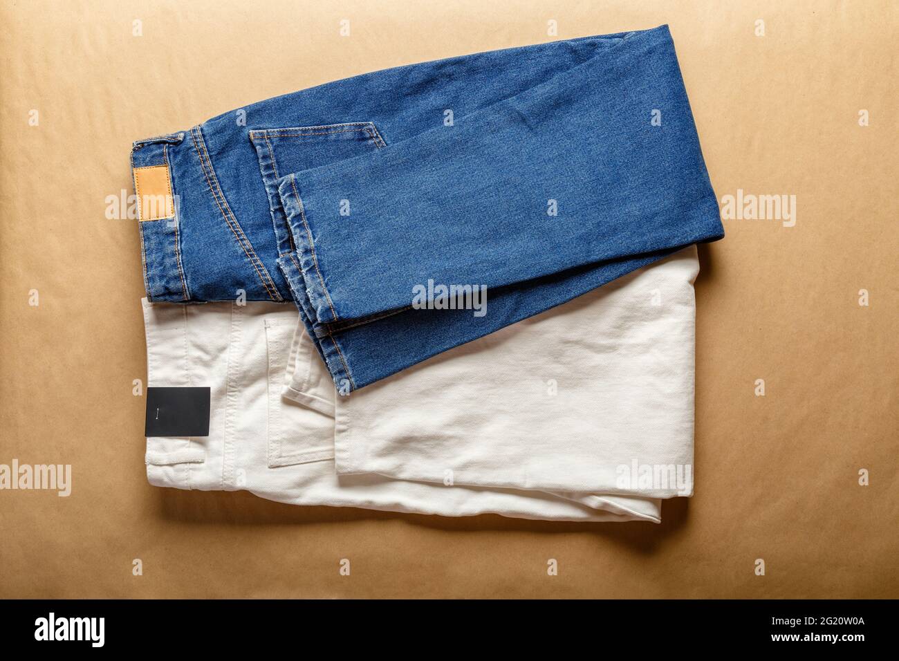 Pantalón vaquero azul blanco. Surtido de ropa vaquera de diferentes colores  en tienda con etiqueta de emty. Pantalones vaqueros blancos, jeans azules  sobre mesa marrón Fotografía de stock - Alamy