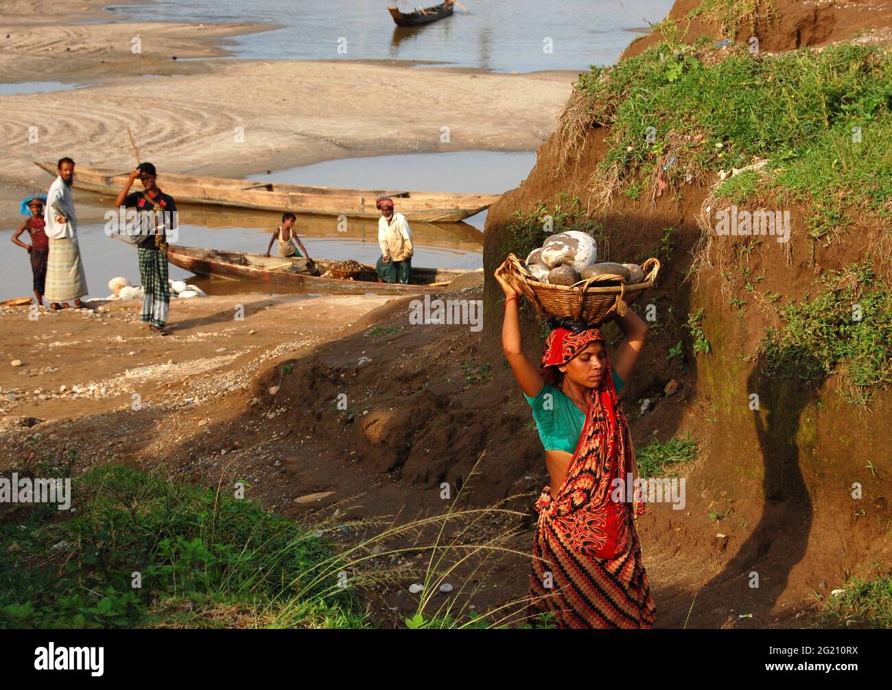 Mujer que transporta arena de río desde el río Meghna, Bangladesh, que se utilizará para la construcción de edificios urbanos. Para fines de construcción, se prefiere arena de río baja en salinidad. Sin embargo, se trata de un negocio grande y a menudo no regulado en manos de sindicatos políticos. Ellos extraen voluntariamente la arena, destruyendo la vida acuática mientras explotan a las mujeres para llevar a cabo el trabajo a salarios marginales. Bangladesh. Foto de stock