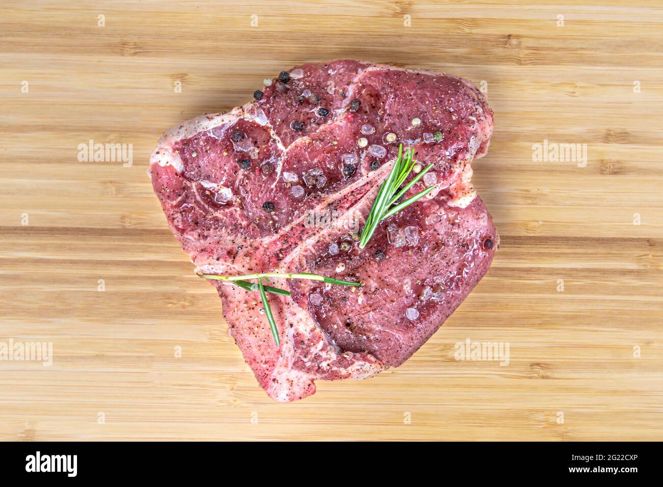 Black angus t bone steak aislado hueso de carne cruda. Filete de ternera  cortado para barbacoa. Lomo de carne bovina sin cocinar, condimento de sal  y romero, puerto deportivo Fotografía de stock -