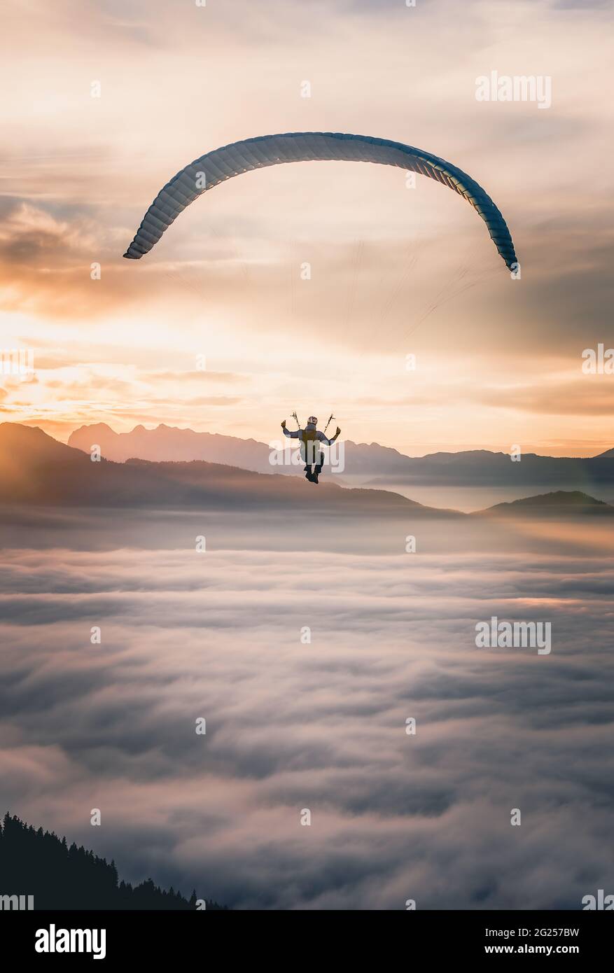 Hombre parapente por encima de las nubes al atardecer, Salzburgo, Austria Foto de stock