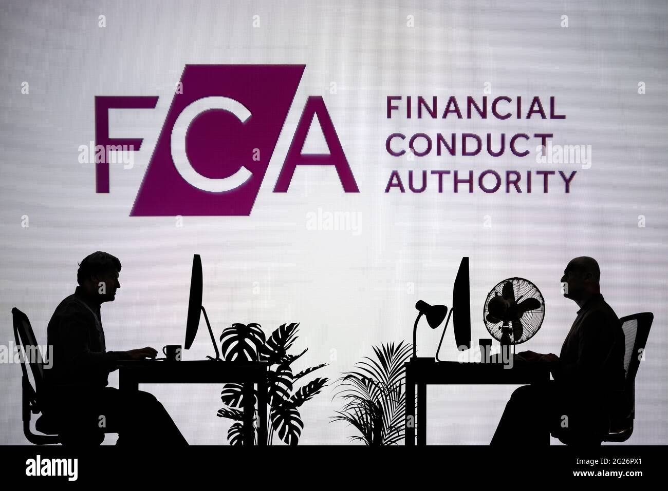 El logotipo de la FCA se ve en una pantalla LED de fondo, mientras que dos personas con siluetas trabajan en un entorno de oficina (sólo para uso editorial) Foto de stock