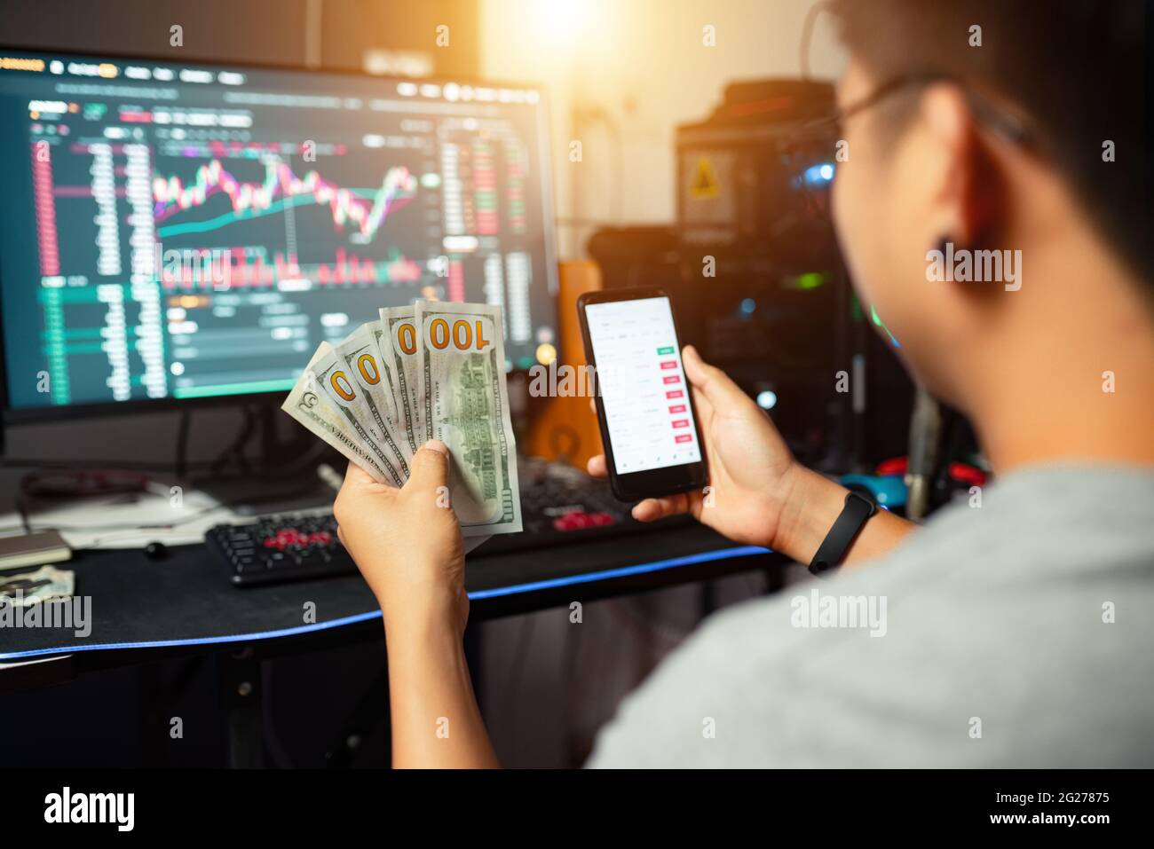 Un joven comerciante que sostiene el dólar que negocia el intercambio de dinero con el blockchain del cripto en línea Foto de stock