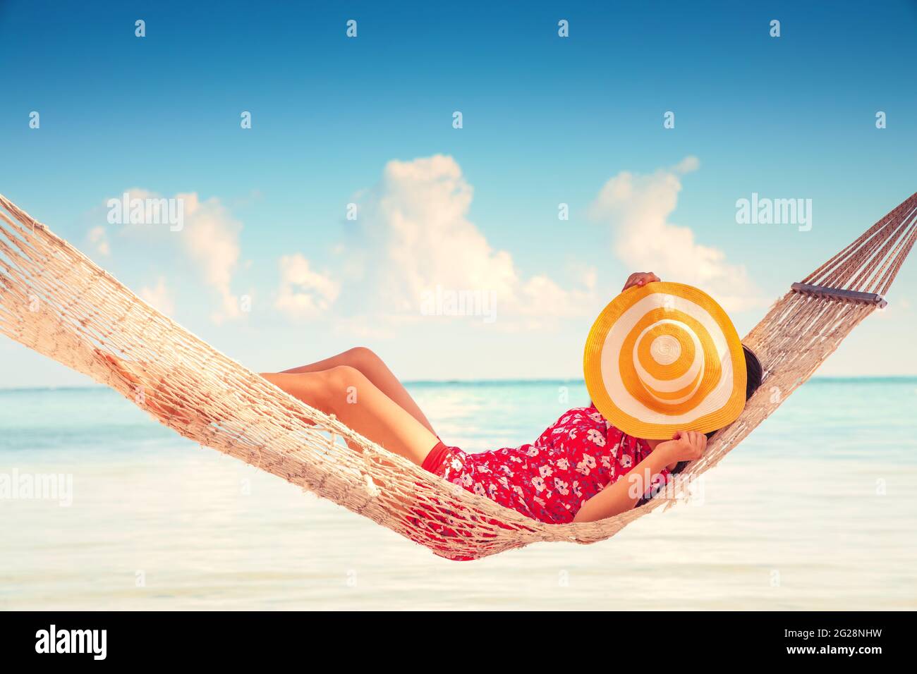 Niña descansando en una hamaca bajo altas palmeras, playa tropical Foto de stock