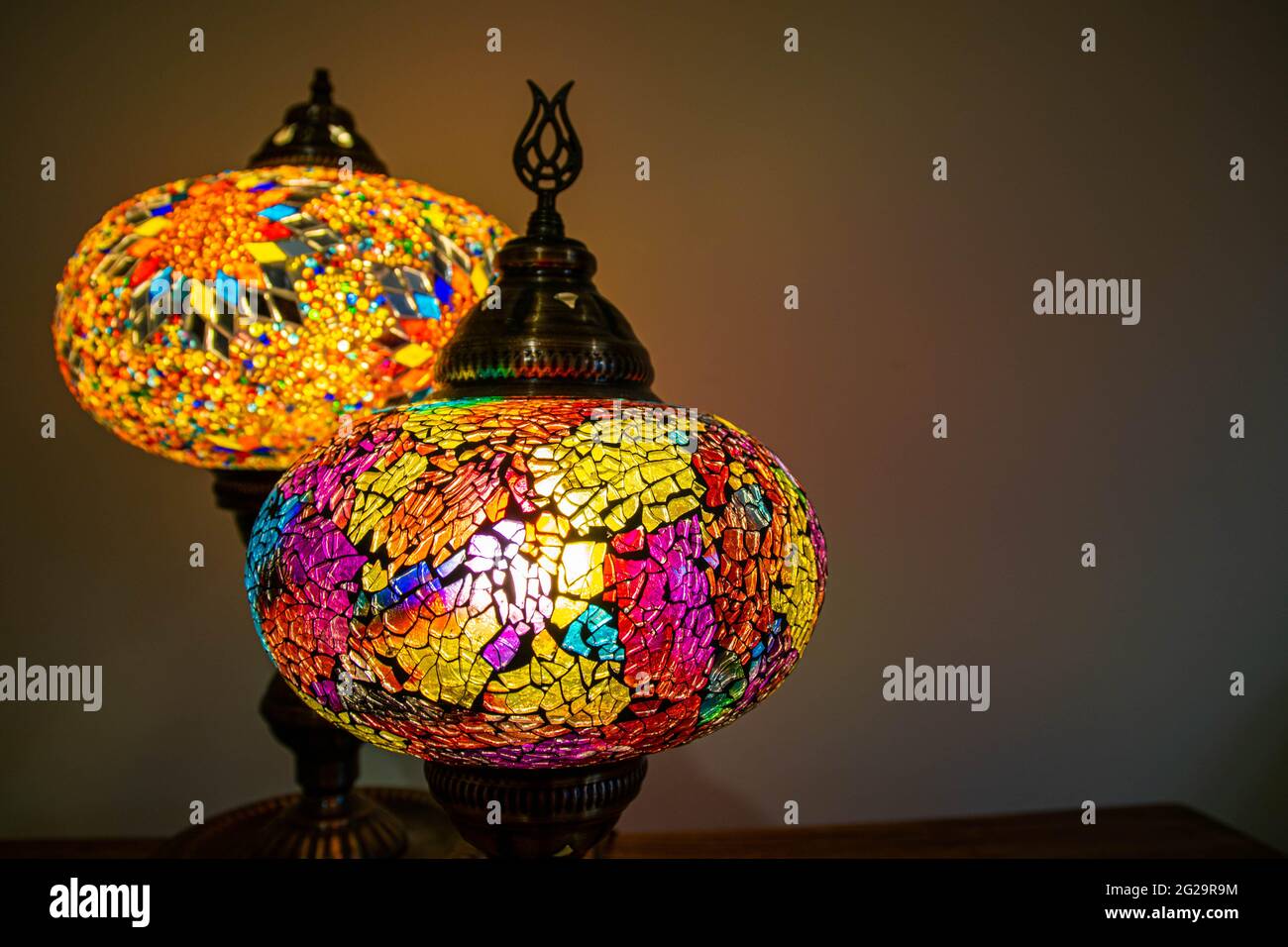 Lámparas de vidrio de manchas artesanales turcas marroquíes iluminadas.  Vibrante y colorido que aporta a la decoración del hogar un ambiente  acogedor. Espacio de copia, fondo borroso, inicio sty Fotografía de stock -