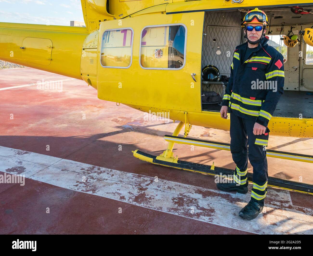 Un bombero de rescate de pie junto a un helicóptero amarillo mirando a la  cámara Fotografía de stock - Alamy